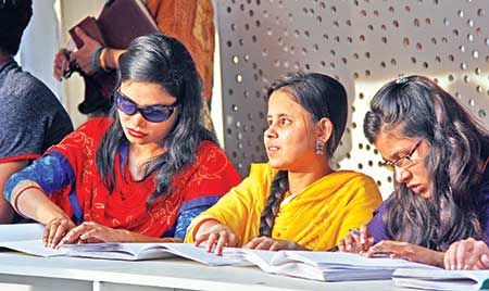 Vision impaired girls reading books at a special stall at the Amar Ekushey Book Fair on Sunday. 	PHOTO: Ashik Mohammad