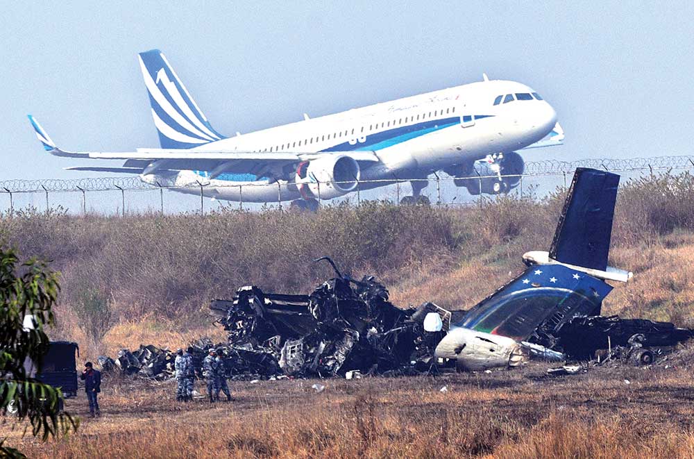 An airplane takes off at the international airport in Kathmandu on Tuesday, near the wreckage of a US-Bangla Airlines plane that crashed on Monday.    photo: AFP 