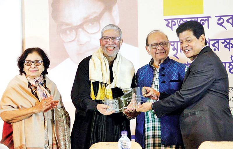 Shafiuzzaman Khan Lodi receiving his award from Syed Hasan Imama and Farooque. Anwara Syed Haq can also be seen on stage.