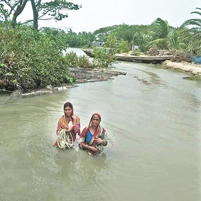 two women wading through stranded water in the same area