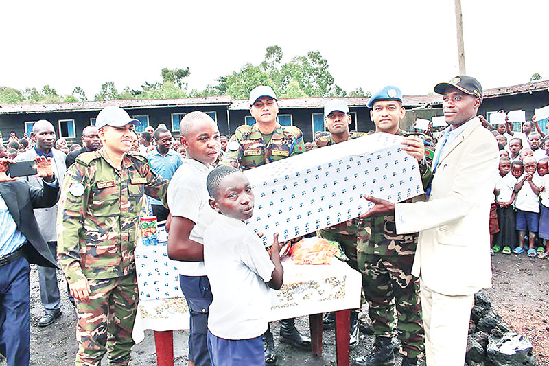 Lt Col Shahnnenul Islam Khan, Contingent commander BENENGR -10, providing books, pencils etc to the students of Mboga School at Goma in DRC recently.	PHOTO: OBSERVER