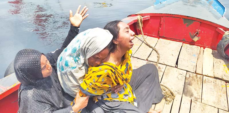 A heavy duty salvage vessel Prottaya on Monday pulled out the ill-fated launch that sank after being rammed by a cargo vessel on the Shitalakkahya River on Sunday. (Inset) Relatives of a victim seen wailing on a boat waiting for the news of their loved one.   	photo : pappu bhattacharyia