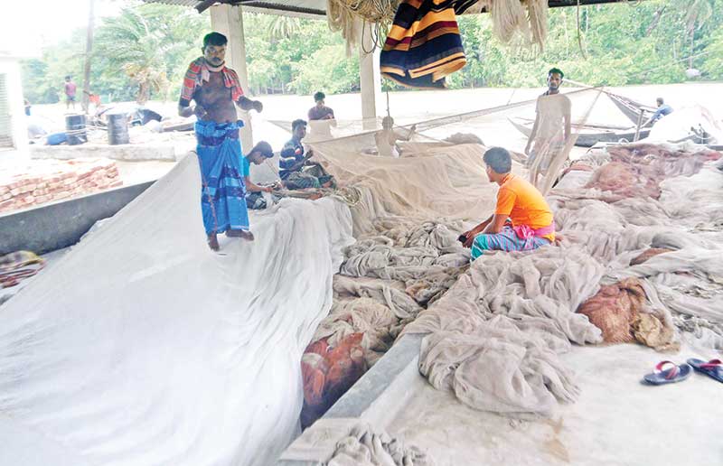 The photo shows sea fishers in Morrelganj Upazila repairing nets.	photo: observer