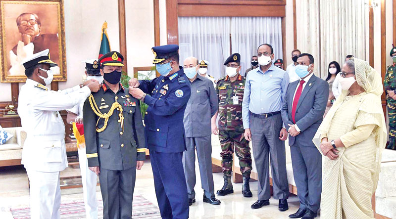 Newly-appointed chief of the Bangladesh Army General SM Shafiuddin Ahmed being adorned with the rank badge by Navy Chief Admiral M Shahin Iqbal and Air Force Chief Air Marshal Sheikh Abdul Hannan as Prime Minister Sheikh Hasina looks on at Ganabhaban on Thursday. 	PHOTO: PID