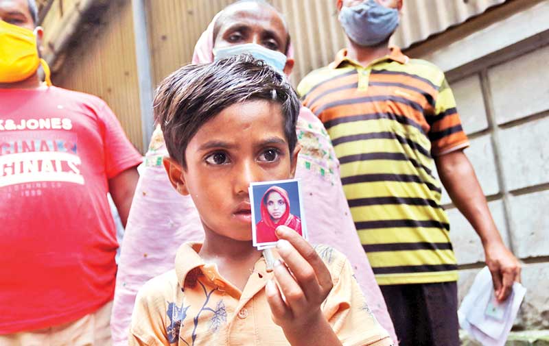 A kid shows the picture of his mother as samples were taken for DNA tests at Dhaka Medical College Hospital on Saturday for identifying the charred bodies of the victims of the devastating fire at Hashem Foods factory in Rupganj upazila of Narayanganj. 	PHOTO: OBSERVER