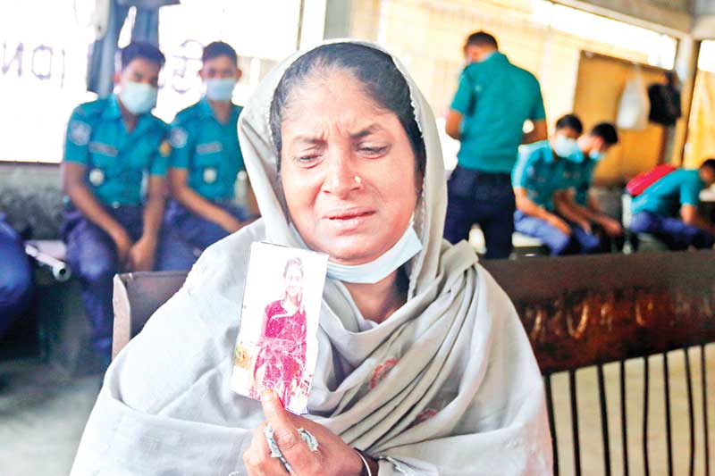 A kid shows the picture of his mother as samples were taken for DNA tests at Dhaka Medical College Hospital on Saturday for identifying the charred bodies of the victims of the devastating fire at Hashem Foods factory in Rupganj upazila of Narayanganj. 	PHOTO: OBSERVER