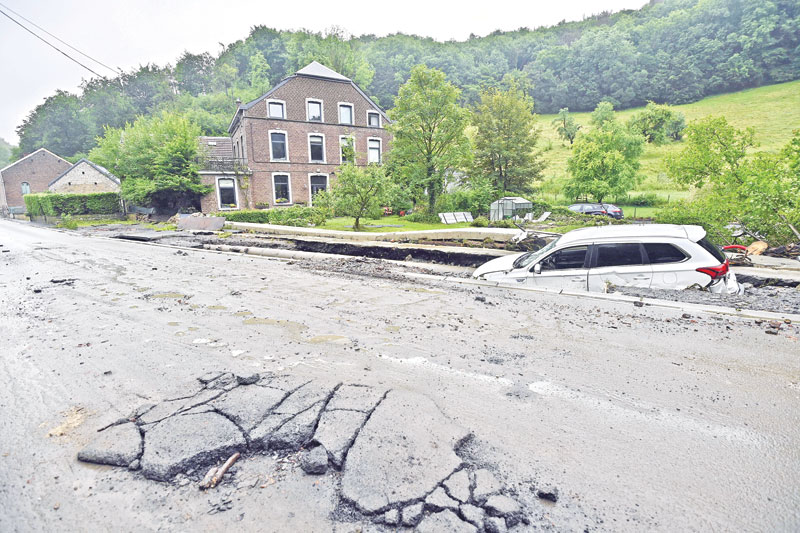 A wrecked car lies half buried besides a damaged road in an area destroyed by recent flood waters in Trooz on 16 July 2021. The death toll from devastating floods in Europe soared to at least 126 on Friday, most in western Germany where emergency responders were frantically searching for missing people.	photo : AFP