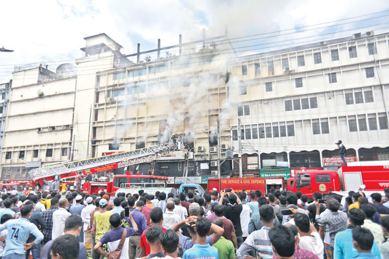 Onlookers crowd the adjacent street as fire-fighters try to douse the flame that spread through a six-storey building at Banani Chairmanbari in the capital on Saturday.	PHOTO: OBSERVER