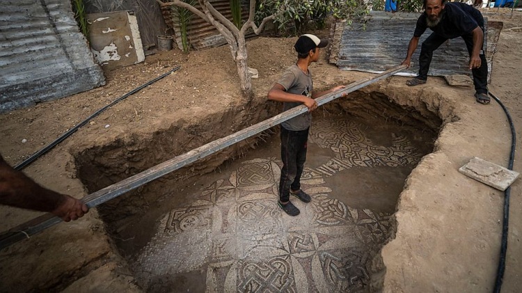 Palestinians clean around a Byzantine-era mosaic floor that was uncovered recently by a farmer in Bureij in central Gaza Strip, Sept. 5, 2022. The man says he stumbled upon it while planting an olive tree last spring and quietly excavated it over several months with his son. Experts say the discovery of the mosaic — which includes 17 well-preserved images of animals and birds — is one of Gaza's greatest archaeological treasures. 
