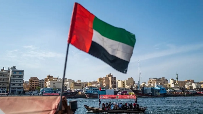 An Emirati flag flies as people travel by boat nearby along the Dubai Creek in Dubai on May 18, 2023. (File photo: Reuters)