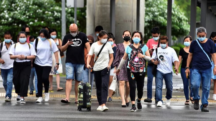 People wearing face masks cross a road amid the coronavirus disease outbreak in Singapore in 2021. (Photo: Reuters)