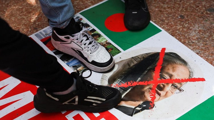 People from the British Bangladeshi community step on an image of Bangladeshi Prime Minister Sheikh Hasina on a banner following her resignation, in a park in East London on August 5, 2024. Photo: Reuters 