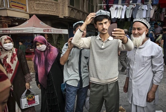 A Uyghur man tries on a hat as he buys new clothes at a market in old Kashgar, Xinjiang Province, China. According to official documents, the city of Kashgar put aside 20,000 yuan annually for 